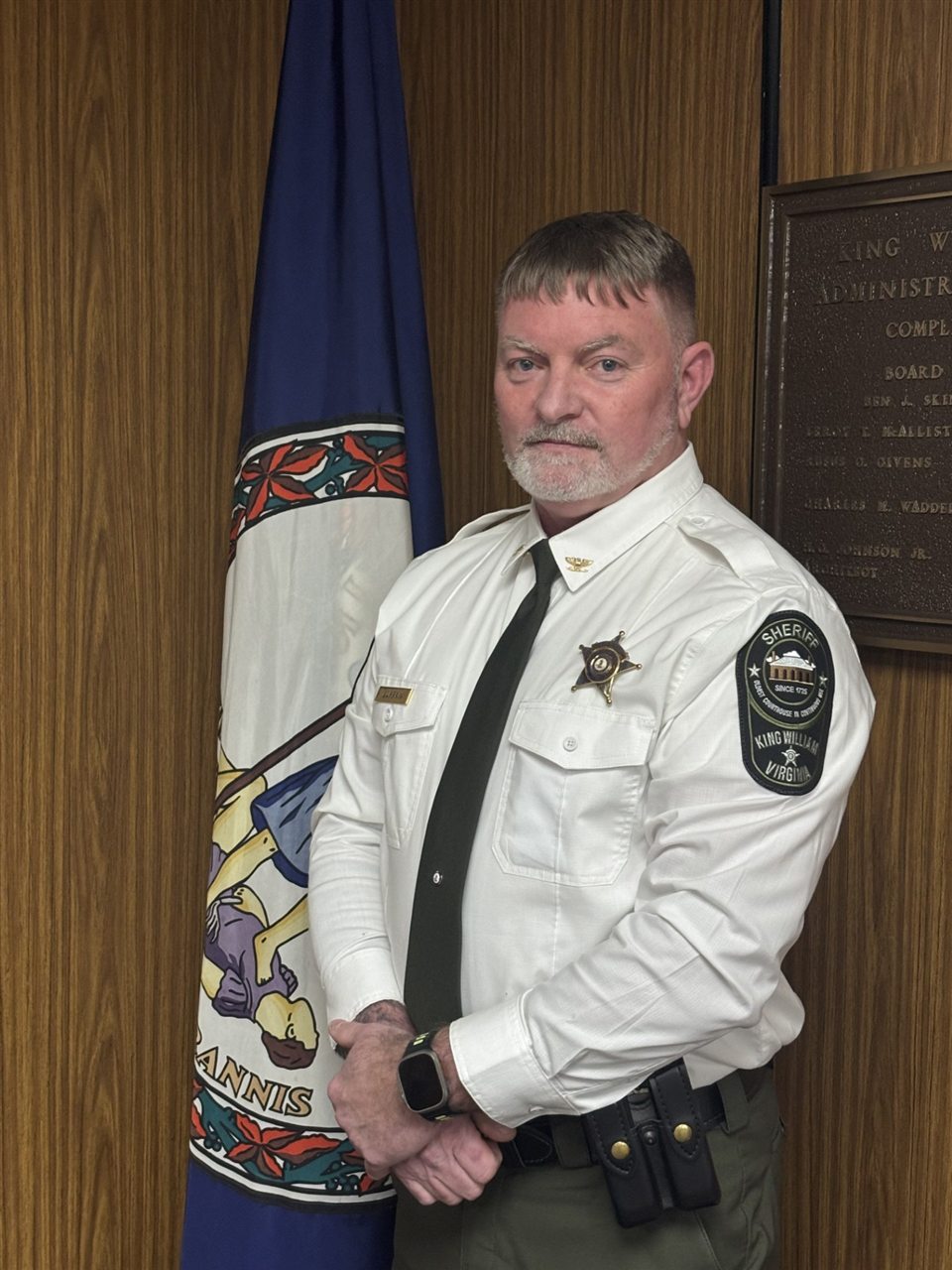 Sheriff T.D. “Don” Lumpkin in uniform, standing beside the Virginia state flag.